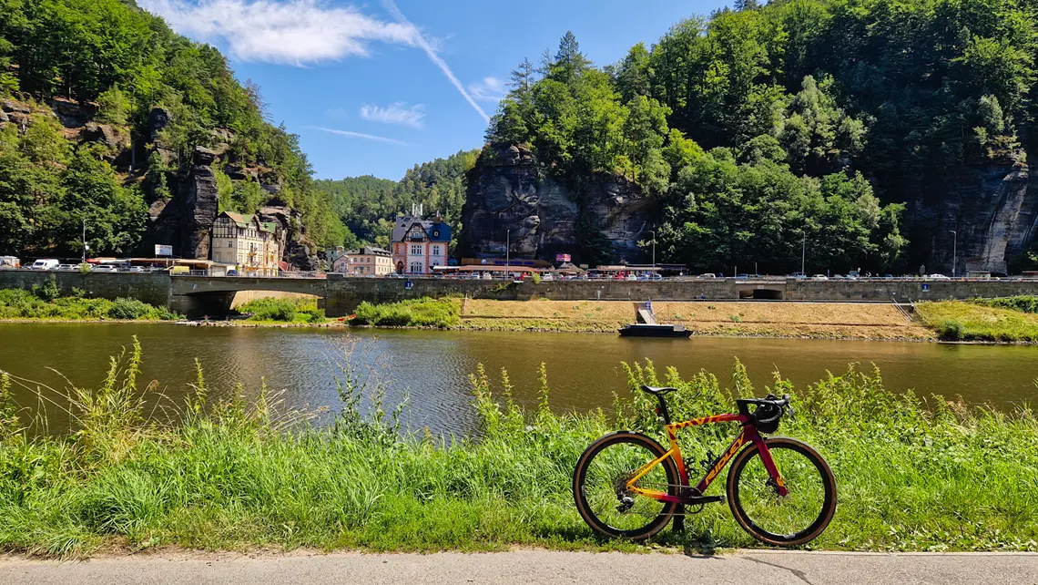 Rower autorki stoi przy rzece z widokiem na małe miasteczko.